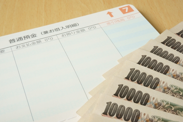 2015年から自衛官妻の2児ママが解説する、お給料から天引きされる防衛省生協の保険代。普通預金の通帳と扇状に並べた1万円札